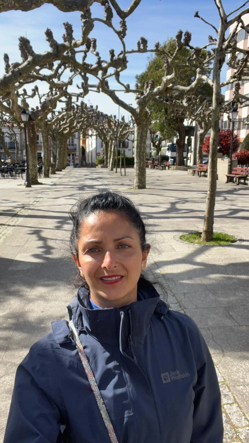 Mit Lida Pilgern - Pilgerreise-Coaching - Eine Person in einem weißen Hemd und einer blau gemusterten Hose steht neben dem massiven, ausladenden Stamm und den Luftwurzeln eines großen Banyanbaums.